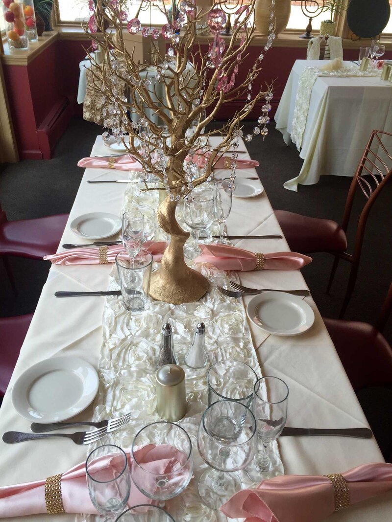 Party table with white table cloth, pink napkins and golden center piece