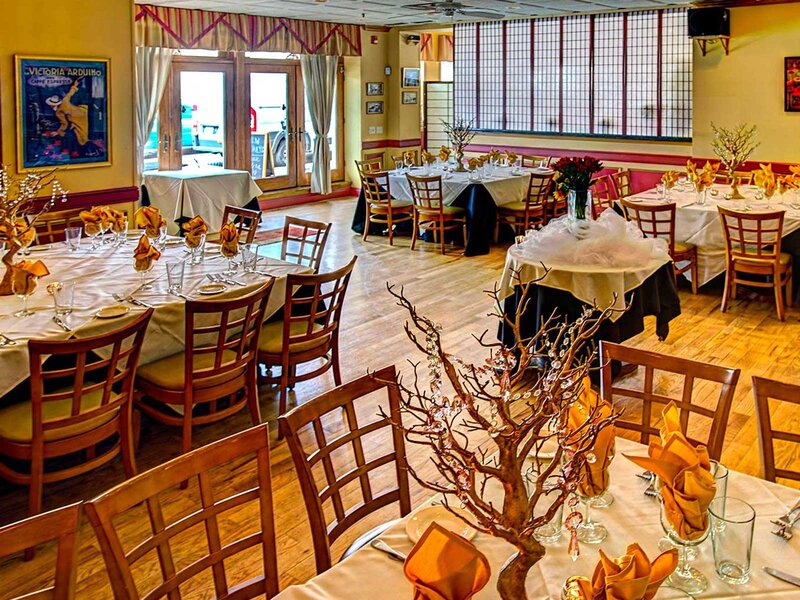 Scala room with set tables with white table cloths, orange napkins and gold center pieces